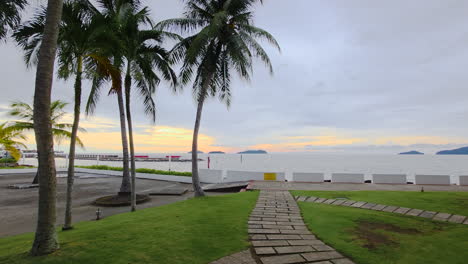 Sunset Sea View from Resort In Kota Kinabalu, Malaysia, With Palm Trees And Stone Path Leading To Waterfront. wide shot