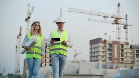 gerente de construcción e ingeniero caminan trabajando en el sitio de construcción usando tableta e impresión.