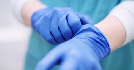 female surgeon putting on protective gloves