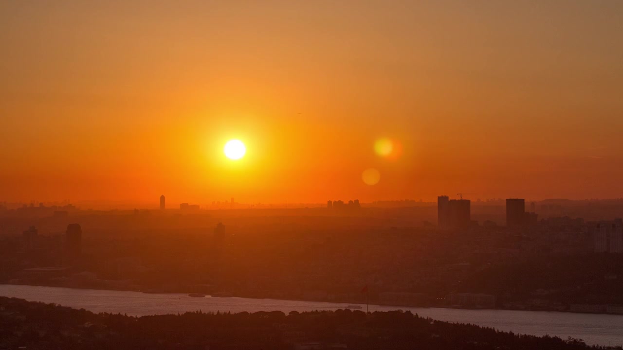 Timelapse de um pôr do sol colorido no Bósforo, visto da parte asiática da cidade, no topo da colina Camlica, com o horizonte de Istambul e a Ponte dos Mártires de 15 de Julho. Céu laranja.