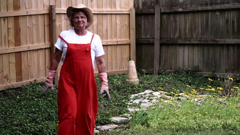 una jardinera desempolvando las manos con guantes después de la jardinería en centerville, ohio - tiro medio completo, cámara lenta