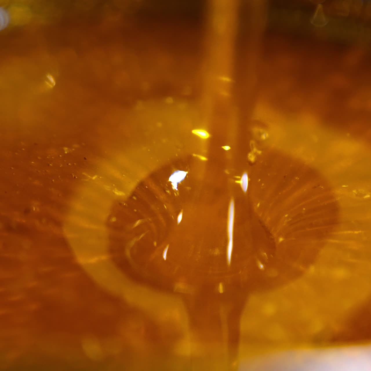 Flow of yellow fresh honey falling into the bowl. Delicious natural healthy organic product after the extraction. Close up