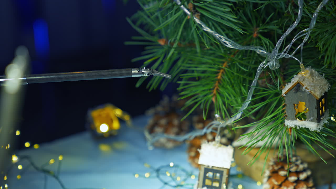 Robotic arm adjusting Christmas decoration on the pine-tree. Little claw dealing with delicate work. Close up.