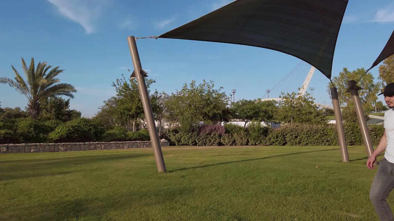 Young man talks on mobile phone while walking through a public park