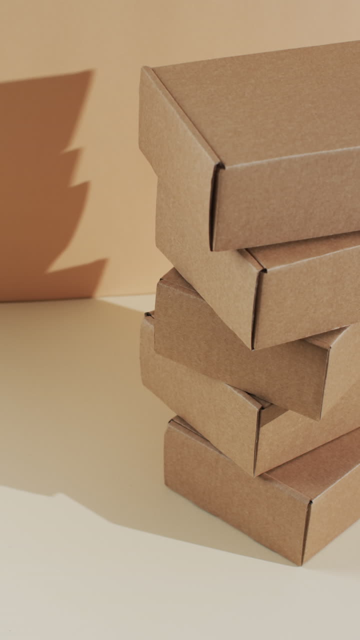 Vertical video of stacked cardboard boxes with copy space over brown background