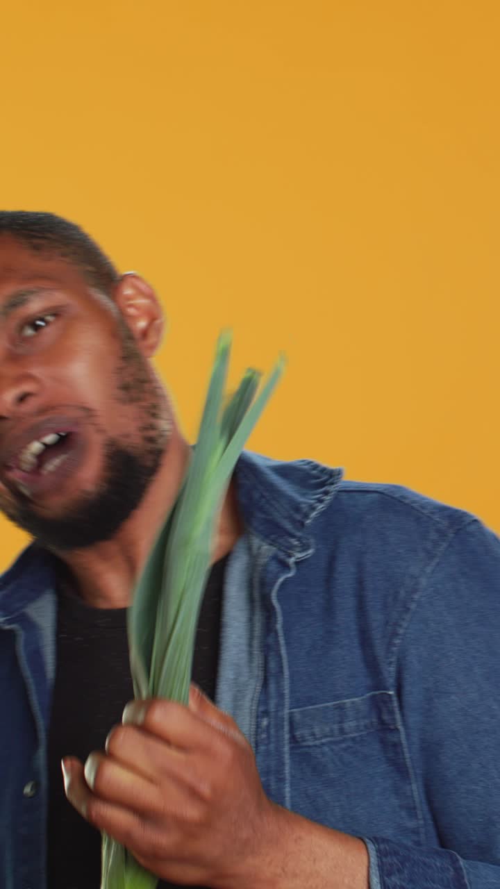 Happy Young Man Plays Leek as a Guitar on Yellow Background