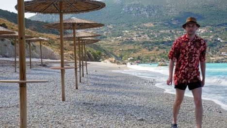 Un-Turista-Masculino-Caminando-Por-La-Orilla-De-Guijarros-En-Una-Hermosa-Playa-De-Agia-Kiriaki,-Zola-En-Kefalonia,-Grecia