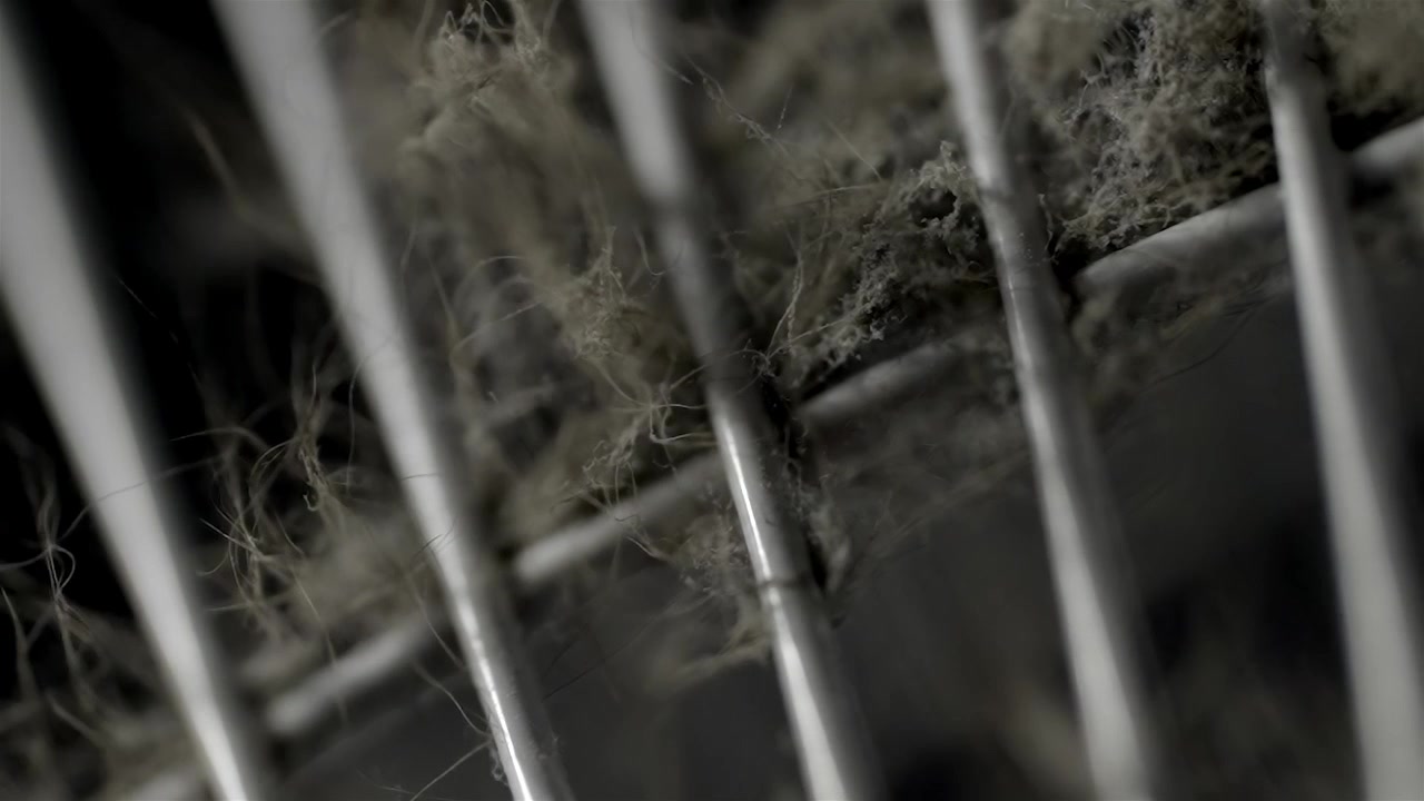 A dusty fan grille fills the close-up frame against a dark blurred background.