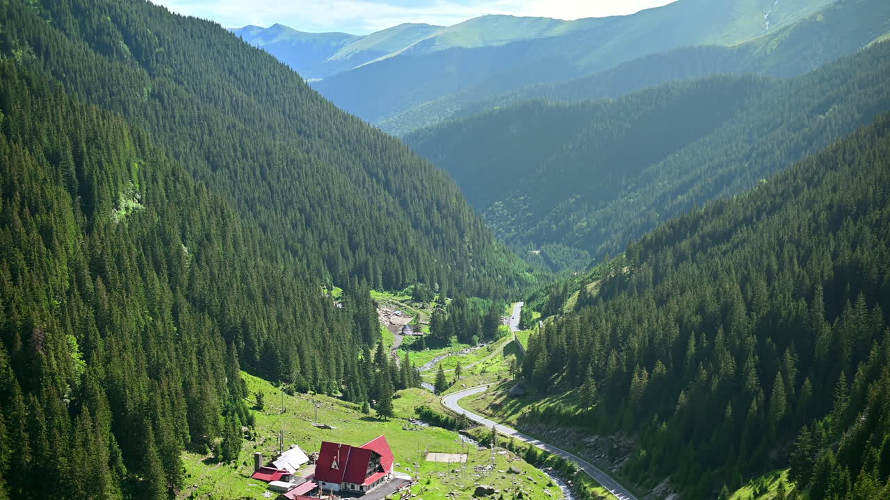 Vista sulla natura nei Carpazi in Romania. Edifici e strada Transfăgărășan in una valle, colline coperte da una foresta rigogliosa