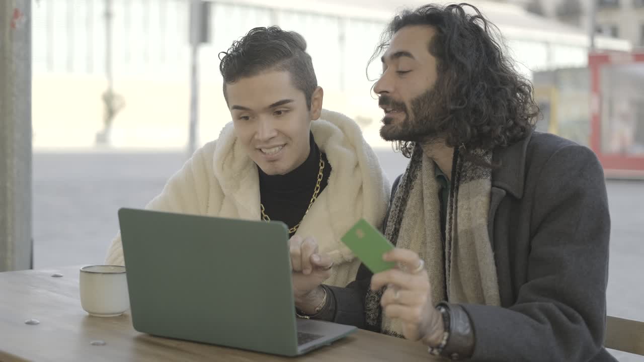 Two men doing online shopping with a laptop and credit card