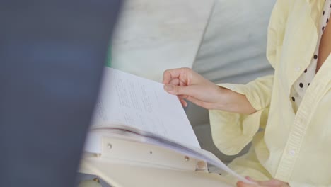 Eine-Frau-Sitzt-Mit-Ihrem-Buch-Und-Einem-Getränk-Auf-Einem-Tisch-Im-Wohnzimmer,-Nahaufnahme,-Aufnahme-Aus-Der-Vogelperspektive