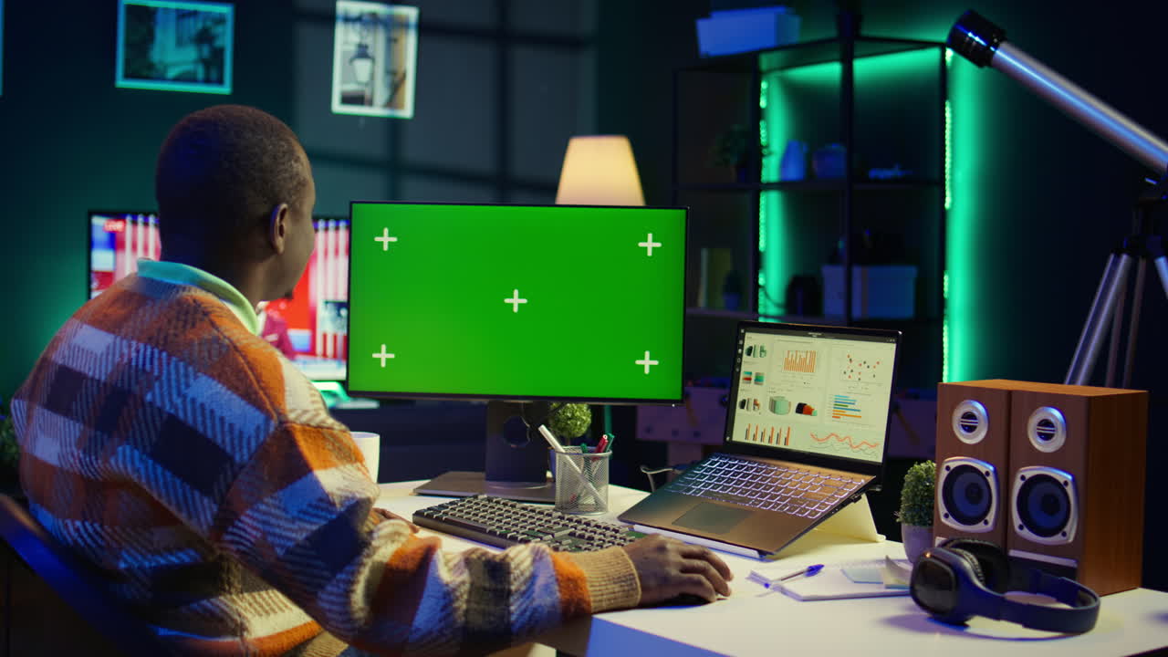 Man working on computer with green screen