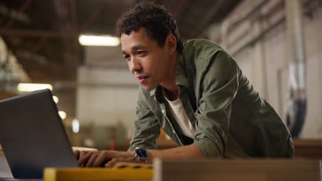 man using laptop in workshop