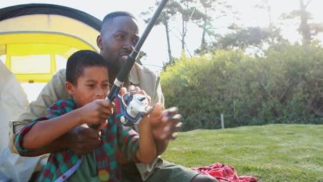 father teaching son how to catch a fish