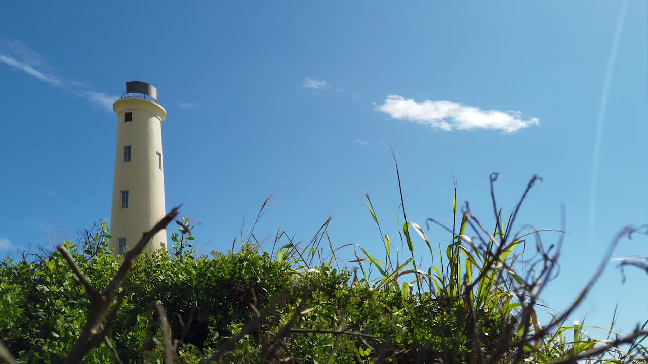 HD Hawaii Kauai Lihue boom down from Ninini Point Lighthouse in background to conceal the lighthouse behind bushes with mostly blue sky