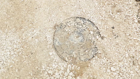 round cast iron manhole lid covered with stones at road under construction in leiria, portugal