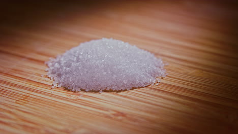 a pile of fine sugar grains on a wooden surface with dramatic lighting, camera orbiting