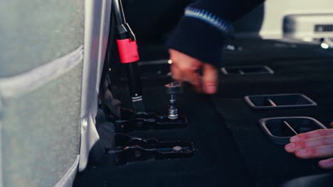a person is using a ratchet wrench to unscrew bolts inside a pajero as part of an interior modification - close up