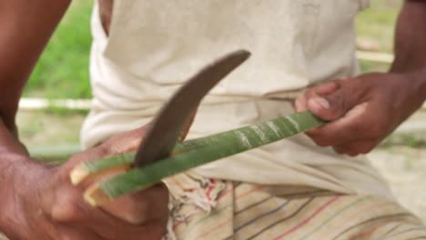 close up of asiatic artisan using a sharp knife for cutting bamboo stick for artisan product