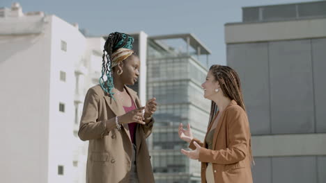 happy women in official suits talking during business party