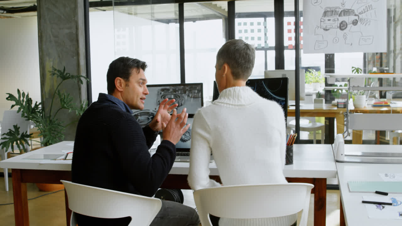 자동차 디자이너 들 이 4k 책상 에서 서로 논의 하고 있다