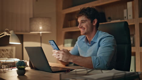 night worker reading message on smartphone sitting office desk close up.