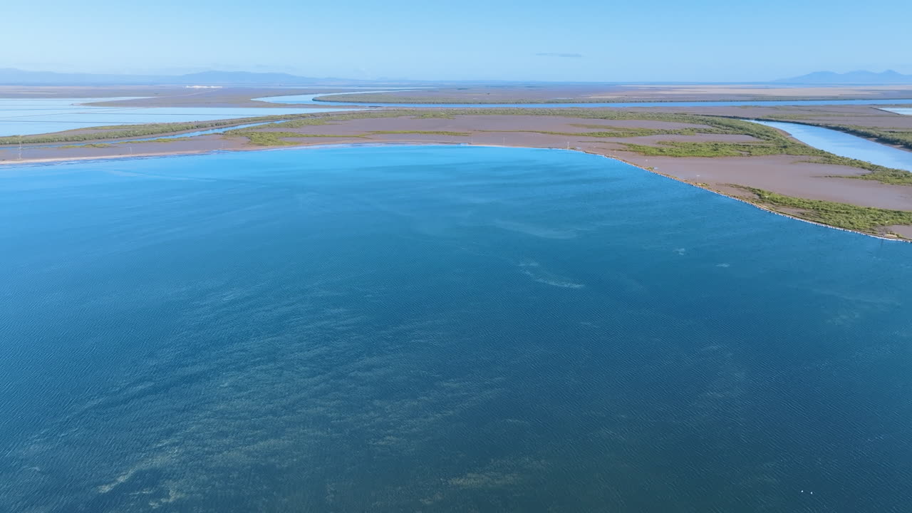 Aerial cruises above the science fiction like landscapes of the Port Alma region near Rockhampton, featuring shallow azure ponds, vibrant green mangroves, and an endless horizon.