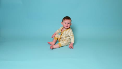 happy toddler baby boy crawls on studio blue background. smiling baby crawling fast on the floor, kid age ten months