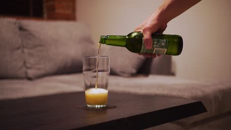 man's hand takes a bottle of beer and pour into a glass, close-up shot