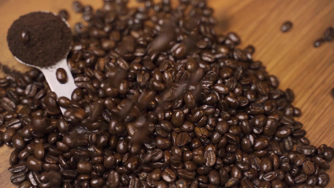 Chicchi di caffè tostati che cadono su una superficie di legno