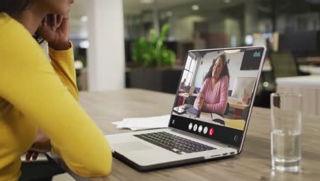 Mujer-Birracial-Usando-Una-Computadora-Portátil-Para-Videollamada,-Con-Un-Colega-De-Negocios-En-La-Pantalla