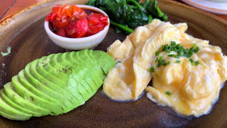 traditional healthy mediterranean breakfast in spain, scrambled eggs with avocado, tomato and spinach, 4k shot