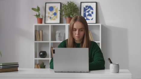 Una-Trabajadora-Concentrada-Está-Escribiendo-Y-Enviando-Mensajes-Con-Una-Computadora-Portátil-Trabajando-Desde-La-Oficina-En-Casa-Retrato-De-Una-Mujer-En-Un-Apartamento-En-La-Sala-De-Estar