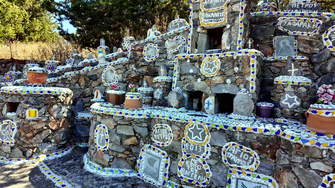 Mosaic shrine decorated with colorful tiles and pottery in a sunlit outdoor setting