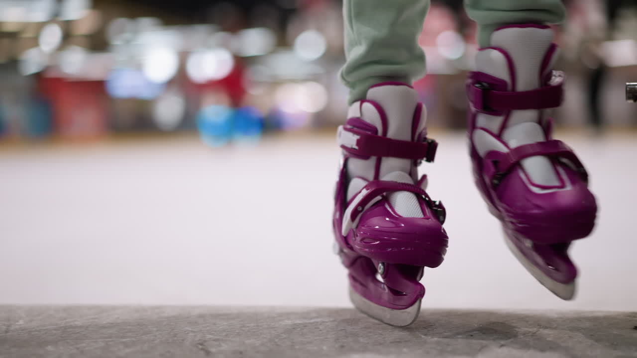 Close-up of a person with purple ice skates stepping out of the ice rink, the focus is on the skates and lower legs, emphasizing the action and movement