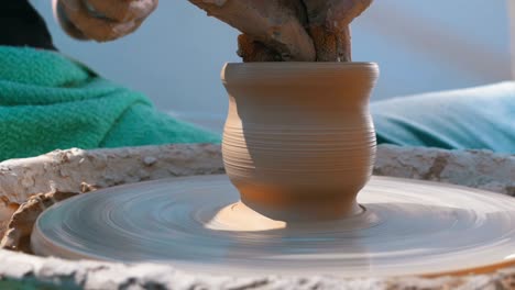 potter's hands work with clay on a potter's wheel