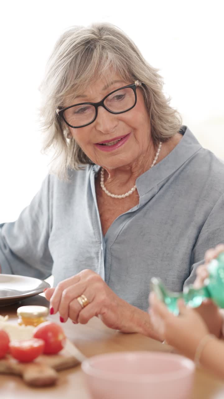Elderly woman wearing glasses and a pearl necklace at a meal