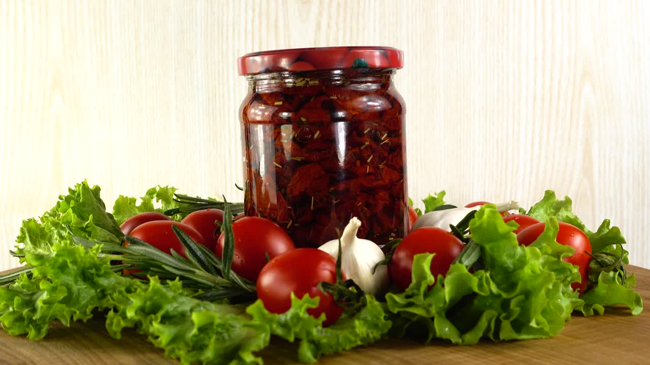 Tomatoes, dried tomatoes, garlic and lettuce leaves on a board. Slow motion