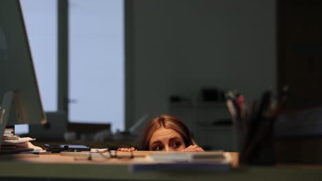 Stressed Woman Peeking Over Desk in Office