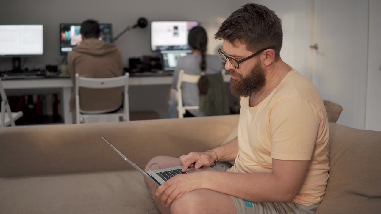 un hombre independiente está trabajando con una computadora portátil sentado en un sofá en un espacio de trabajo conjunto