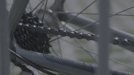 Close-up-shot-of-the-chain-of-a-bicycle-that's-standing-still-with-some-grass-in-the-background-LOG