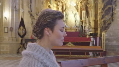 close up profile view of pretty woman praying in catholic church