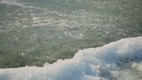 white fresh snow on shore with icy crystal floating on surface