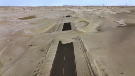 Disparo-De-Drones-Inclinándose-Sobre-La-Carretera-Arenosa-Del-Medio-Desierto,-Día-Soleado-En-Dubai,-Emiratos-Árabes-Unidos