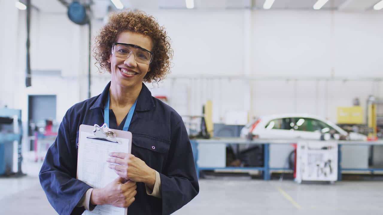 retrato de una tutora con gafas de seguridad que enseña aprendizaje de mecánica automotriz en la universidad