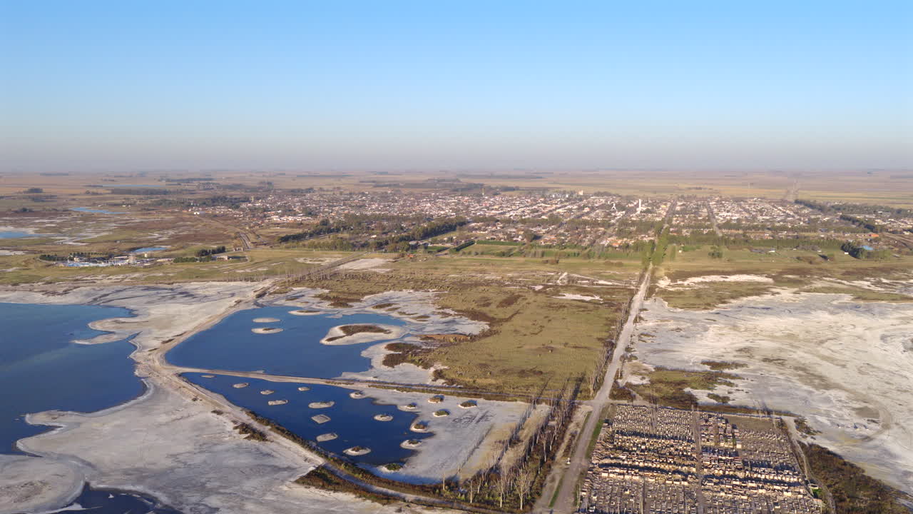 Aerial fly at coastal landscape with Epecuén Lake salt ponds with Carhué in the background, Province of Buenos Aires, Argentina
