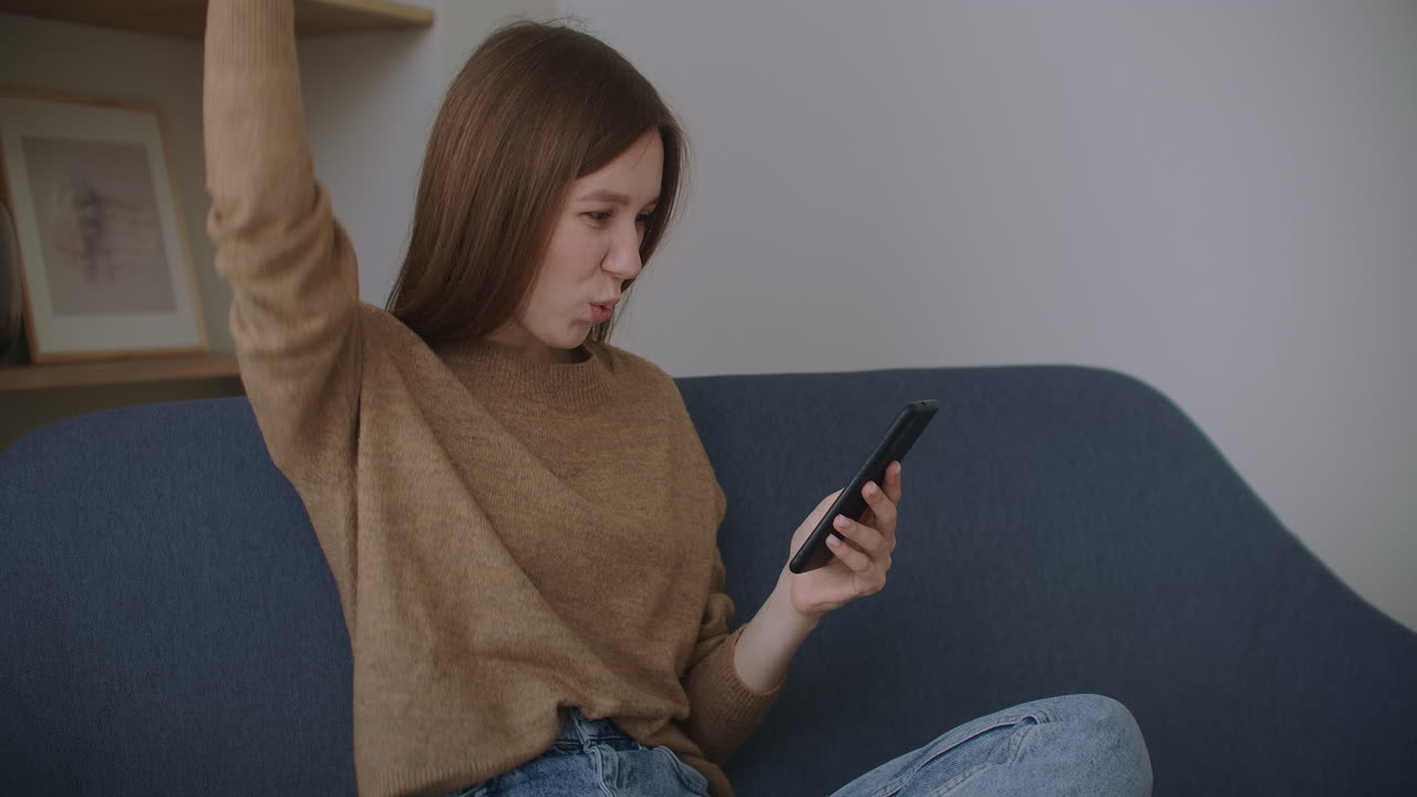 가정 사무실에서 휴대 전화로 메시지를 입력하는 비즈니스 여성. 슬로우 모션으로 전화로 채팅하는 젊은 소녀. 소파에서 스마트폰을 사용하는 젊은 여성의 손을 닫습니다.