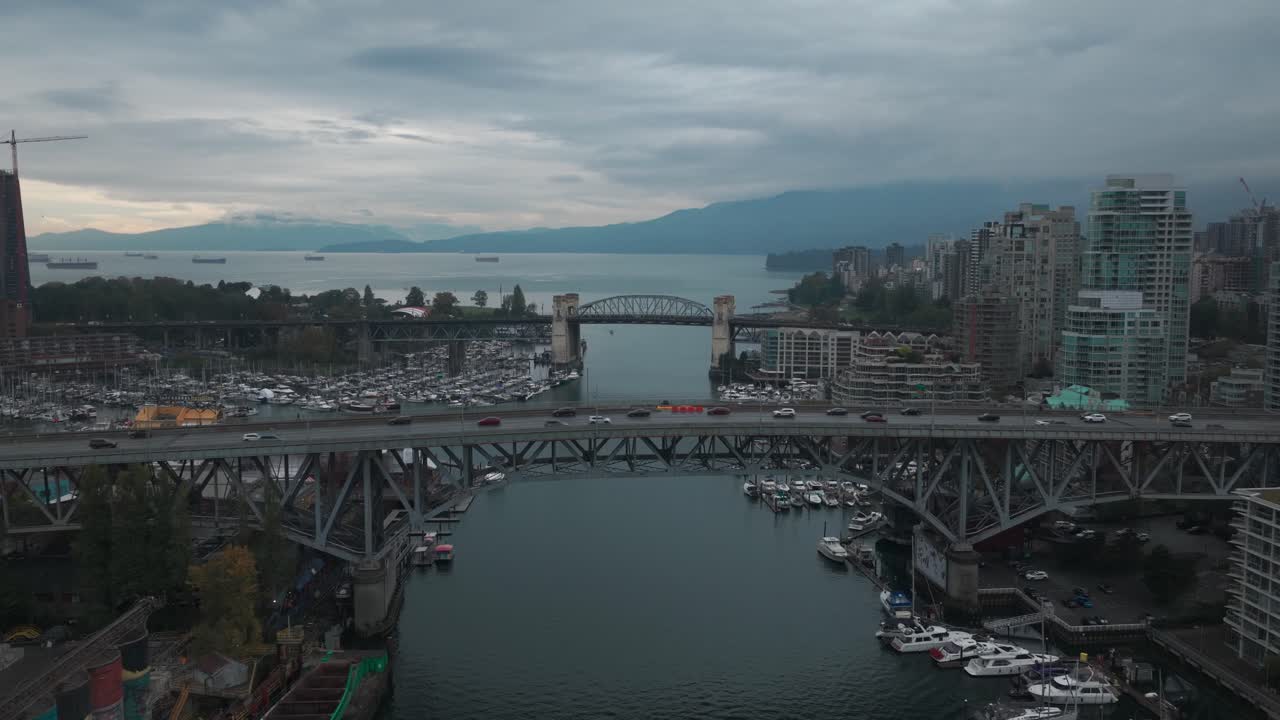Descending close-up aerial shot of the Granville and Burrard bridges across False Creek on a rainy morning in Vancouver, British Columbia, Canada. 4K