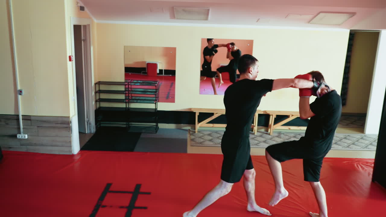Karate practitioners engaged in sparring session inside martial arts gym, fighter delivering strong punches toward opponent face while both demonstrate focus, balance, technique, energy, and combat skill