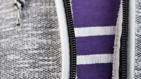 close-up of a zipper on a gray hoodie over a purple striped shirt